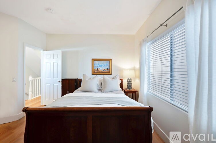 A bedroom with a large bed and a painting on the wall.