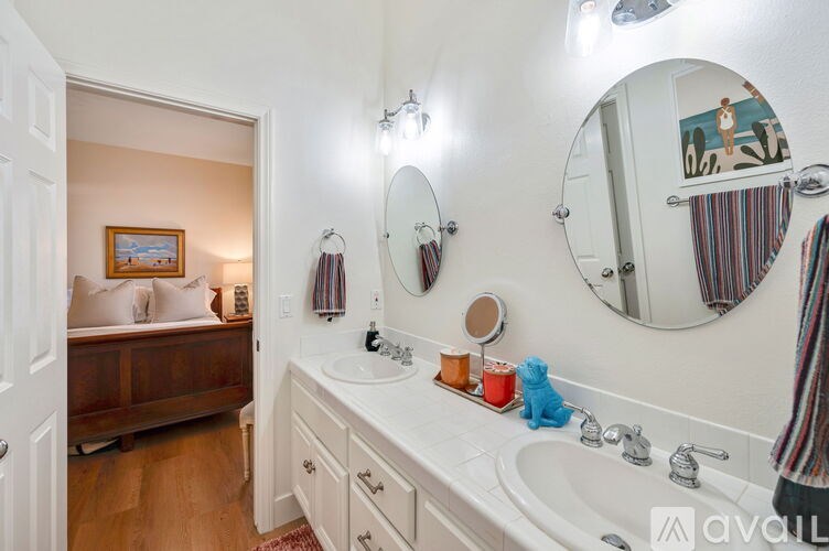 A bathroom with a white sink and a round mirror above it.