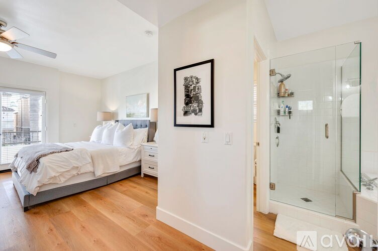 A bedroom with a bed, nightstand, and a framed picture on the wall.