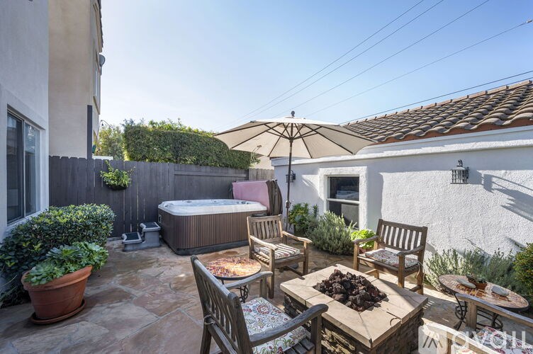 A patio with a table, chairs, and a hot tub.