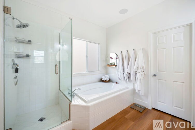 A bathroom with a glass shower door and a bathtub with a white towel hanging on the wall.