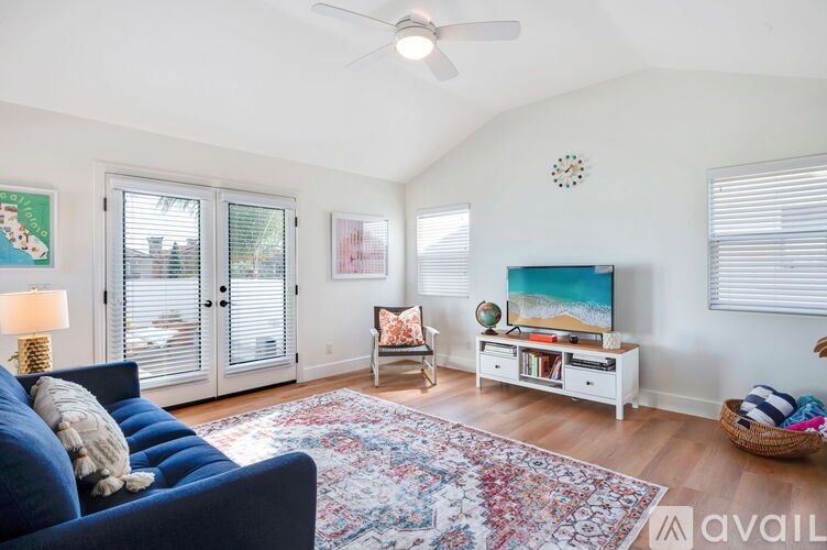 A living room with a blue couch and a fan on the ceiling.
