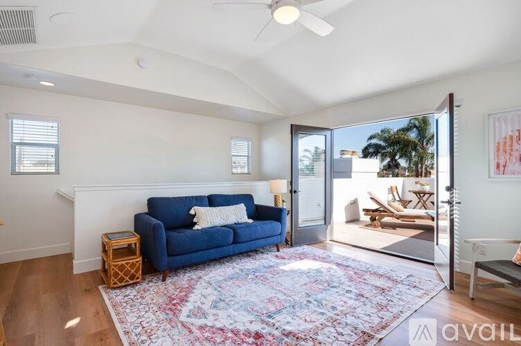 A living room with a blue couch and a rug.