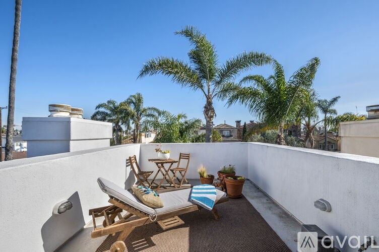 A patio with a table, chairs, and a couch with a cushion on it.