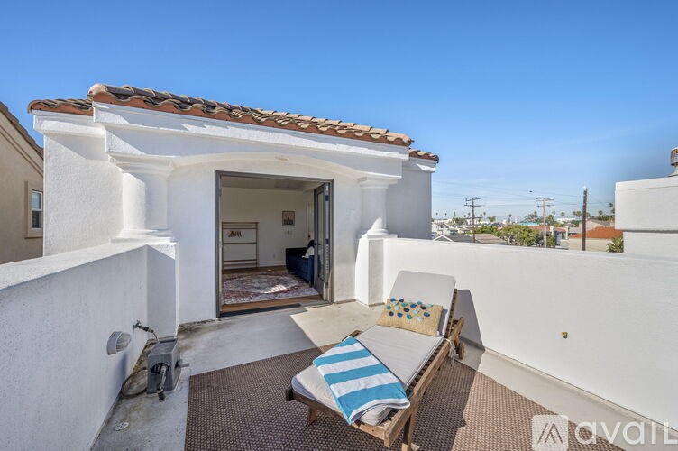 A sunny patio with a white building and a striped cushion on a chair.