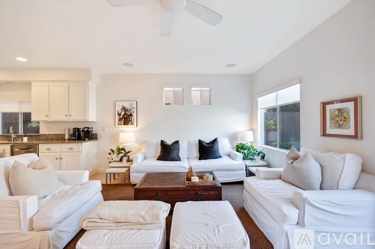 A living room with white furniture and a ceiling fan.
