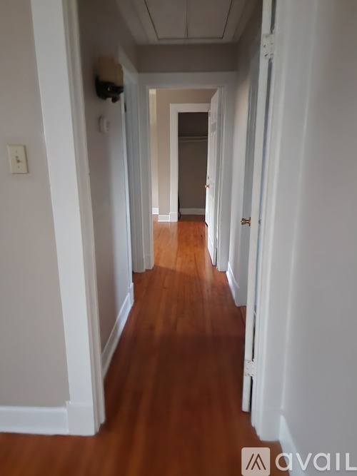 A long hallway with white walls and wood flooring.