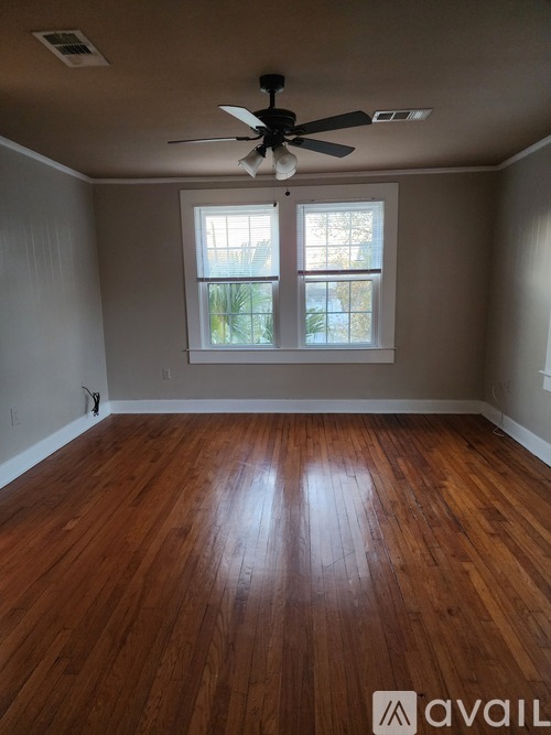 A room with a ceiling fan and wooden flooring.