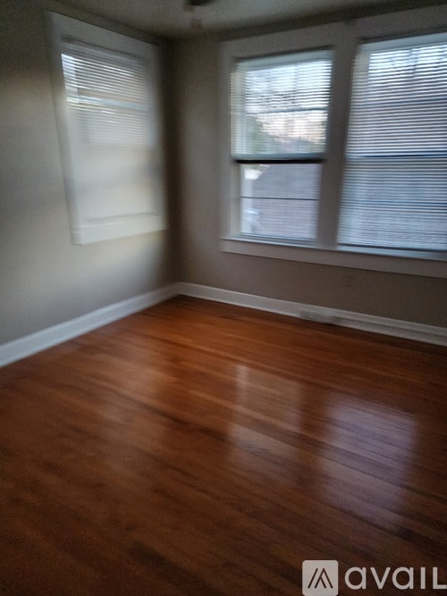 A room with wooden floors and a window with blinds.