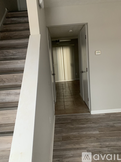 A hallway with a staircase on the left and a door on the right.