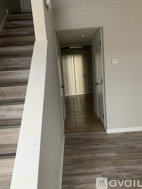 A hallway with a staircase on the left and a door on the right.