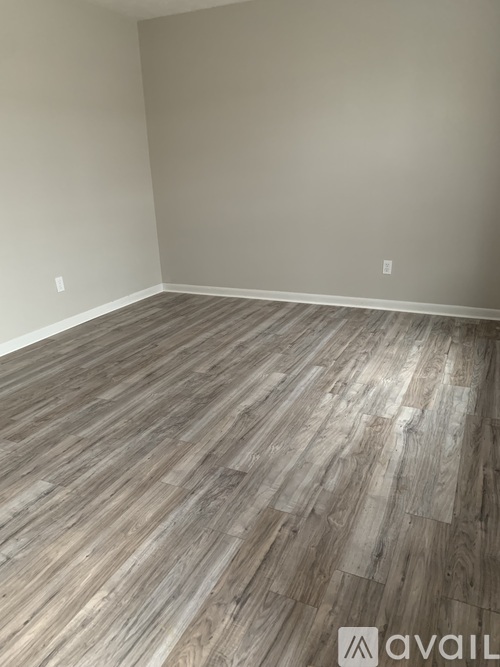 A room with wooden flooring and a wall socket.