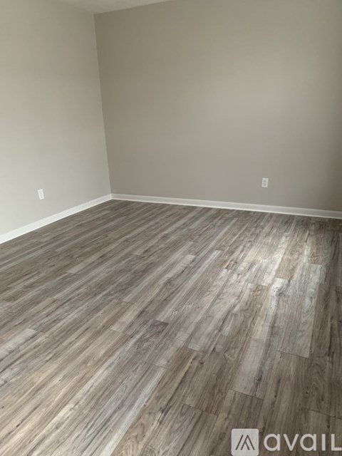A room with wooden flooring and a wall socket.