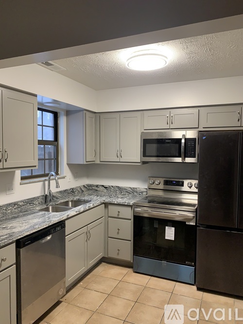 A kitchen with a black refrigerator, a black oven, and a black dishwasher.