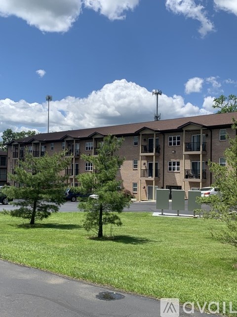 Apartment complex with green grass and trees in front.