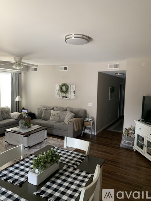 A living room with a checkered table and a grey couch.