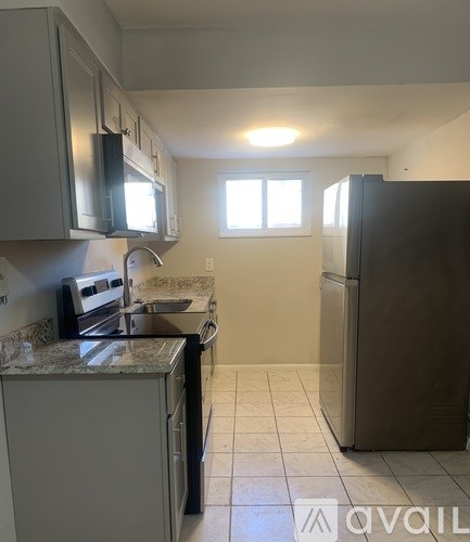 A kitchen with a refrigerator, microwave, oven, and sink.