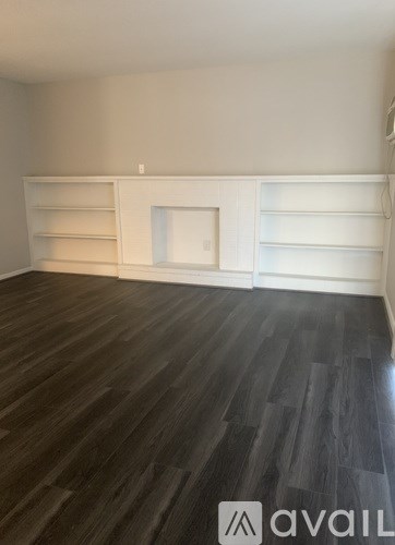 A room with wooden flooring and white shelves.