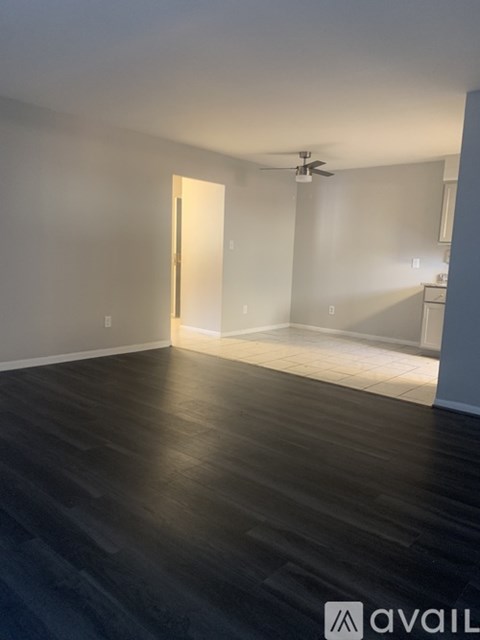 A room with a ceiling fan and a door leading to another room.