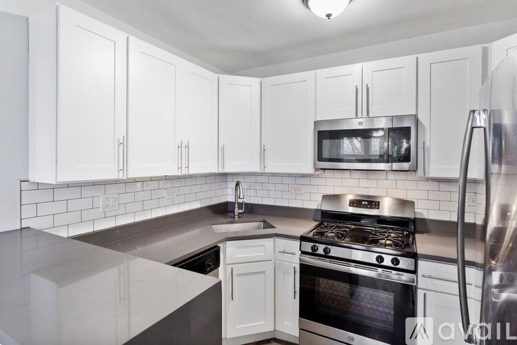 A kitchen with white cabinets and a stainless steel refrigerator.