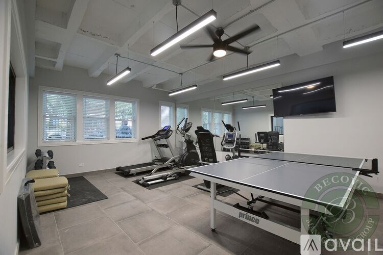 A well-lit room with a ping pong table, treadmills, and exercise equipment.