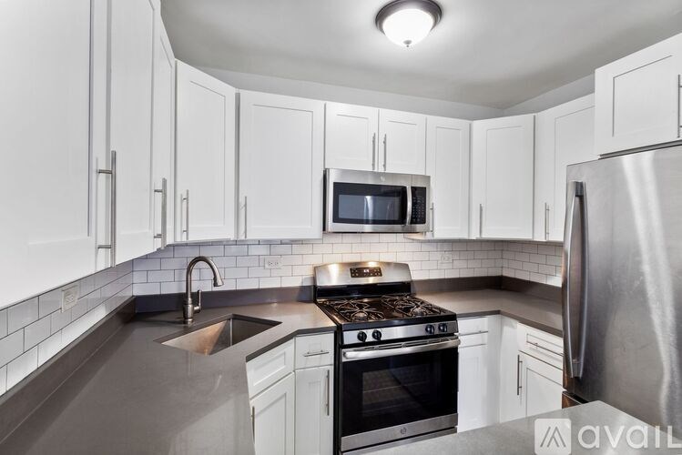 A kitchen with white cabinets and a stainless steel refrigerator.