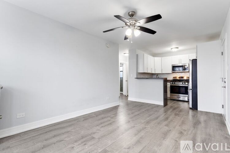 A spacious kitchen and living room with a ceiling fan and hardwood floors.