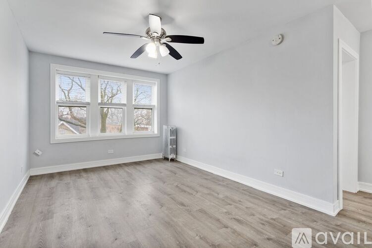 A room with a ceiling fan and a window with a view of trees.