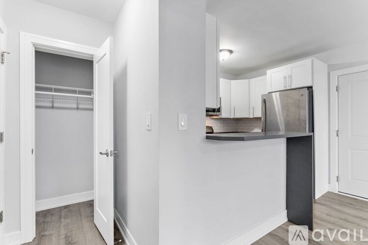 A kitchen area with a refrigerator, cabinets, and a doorway leading to another room.