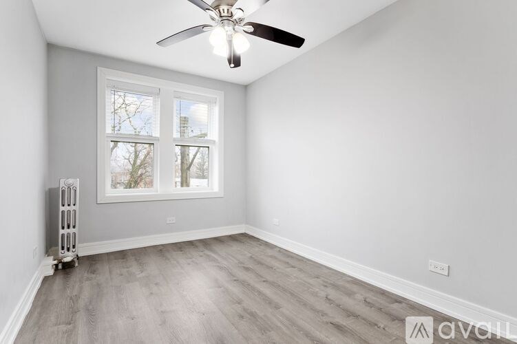 A room with a fan, a window, and a radiator.