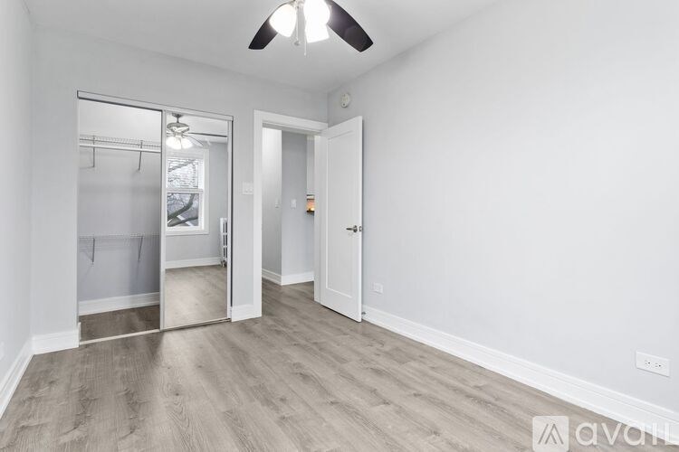A room with a ceiling fan and a door leading to another room.