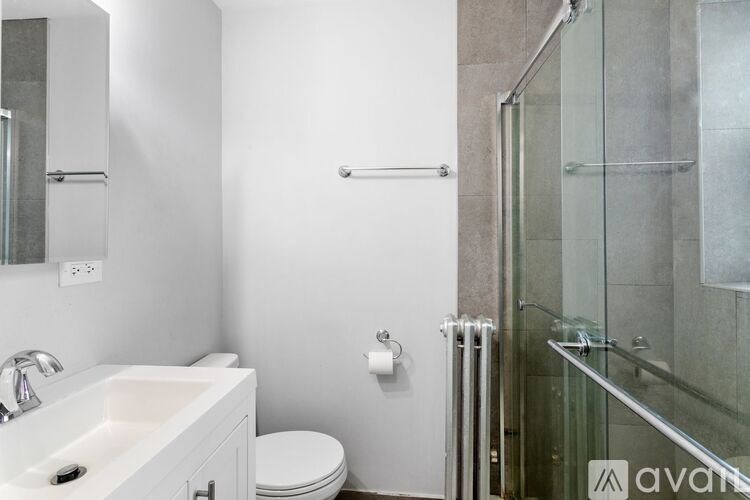 A white sink in a bathroom with a glass shower door.