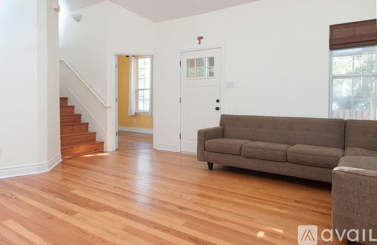 A living room with a couch and a staircase.