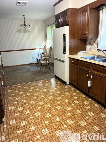 A kitchen with a white fridge and wooden cabinets.
