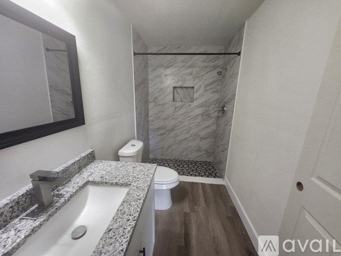 A bathroom with a marble countertop and a walk-in shower.