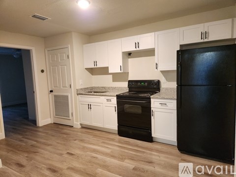 A kitchen with black appliances and white cabinets.