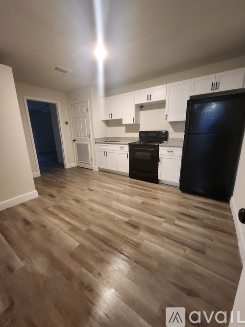 A kitchen with a black fridge and wooden floors.