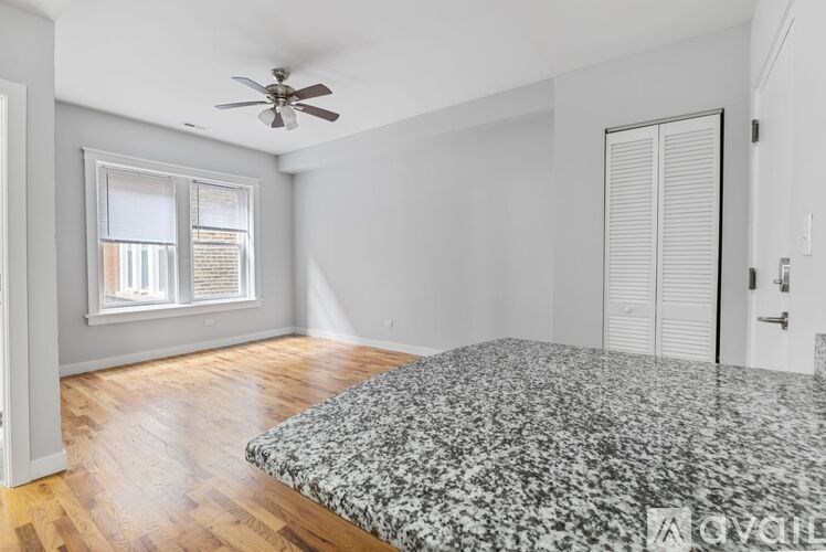 A bedroom with a bed, a ceiling fan, and a window with blinds.