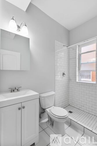 A white bathroom with a toilet, sink, and shower.