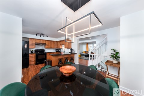 A modern kitchen with a glass table and green chairs.