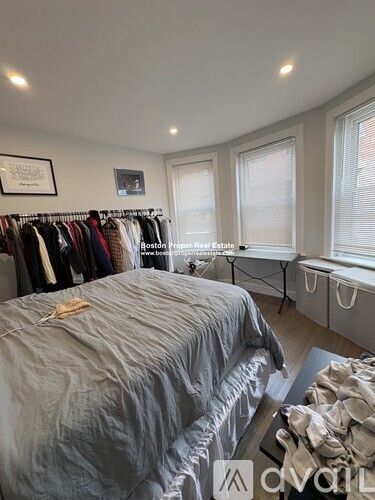 A bedroom with a bed, a window, and a clothing rack.