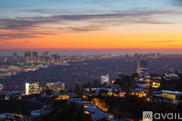 A cityscape at dusk with buildings illuminated against a darkening sky.