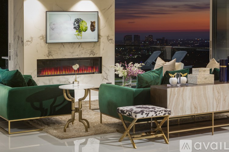 A living room with a fireplace and a view of the city at dusk.