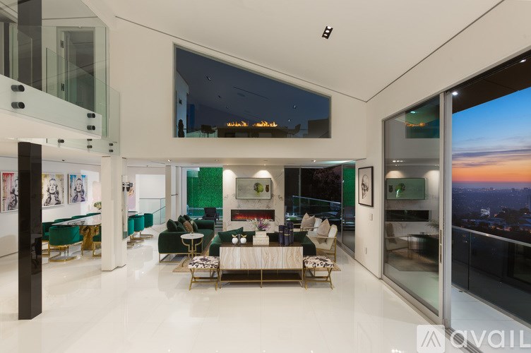 A modern living room with a glass wall overlooking the city at dusk.