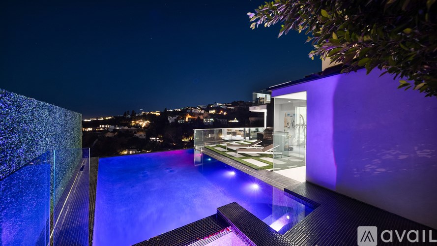 A modern house with a large glass balcony is illuminated at night.