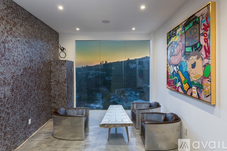 A room with a large painting on the wall and a view of a city skyline through the window.
