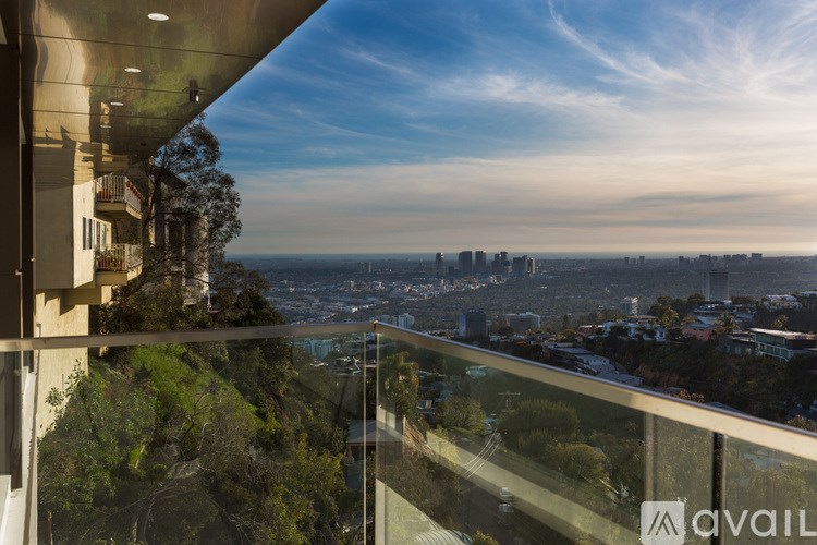 A modern building with a glass balcony overlooking a cityscape.