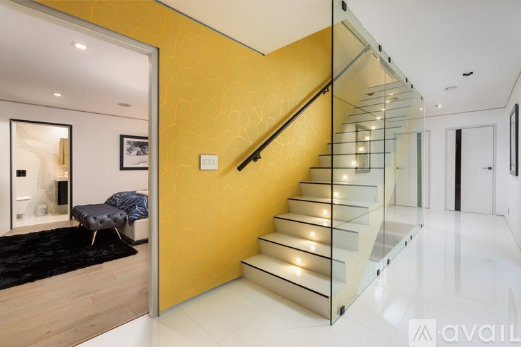 A modern staircase with glass railings and a yellow wall.
