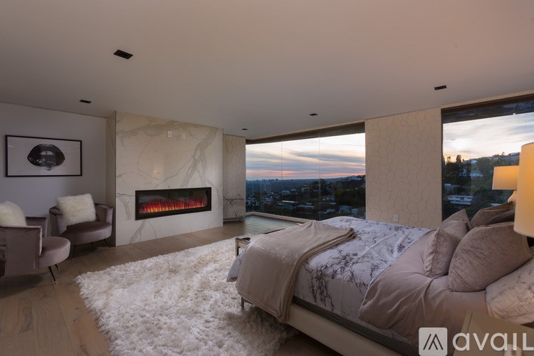 A modern bedroom with a large bed and a fireplace.