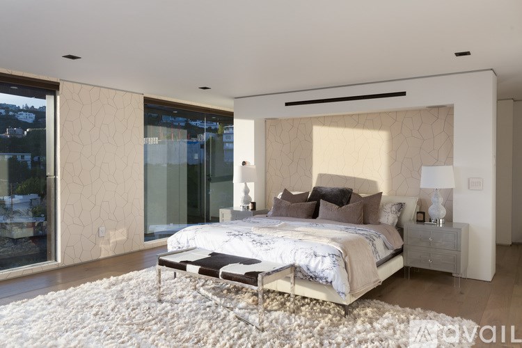 A bedroom with a large bed and a white rug.